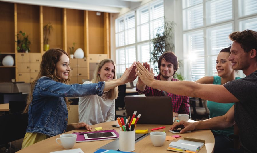 Creative business team putting hands together at the office